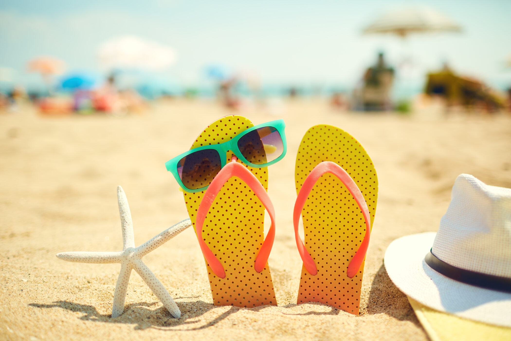 Gelbe Flipflops im Sand mit Seestern und Sonnenbrille: Die perfekte Urlaubsvorbereitung für den Sommerurlaub 2026